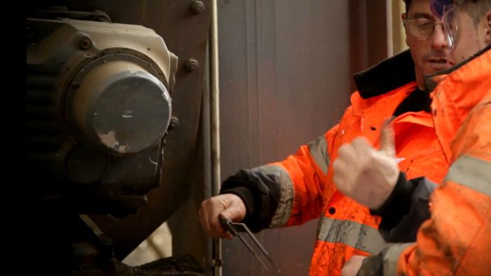 Deux techniciens en tenue haute visibilité inspectent un équipement de convoyeur sur site