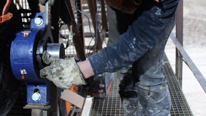 Technicien ganté posant un palier bleu Timken sur une installation de convoyage