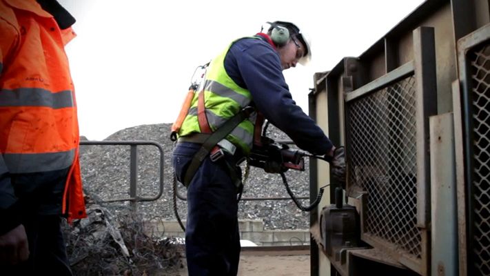 Technicien en gilet de sécurité graissant un équipement de convoyeur avec un outil de graissage portatif